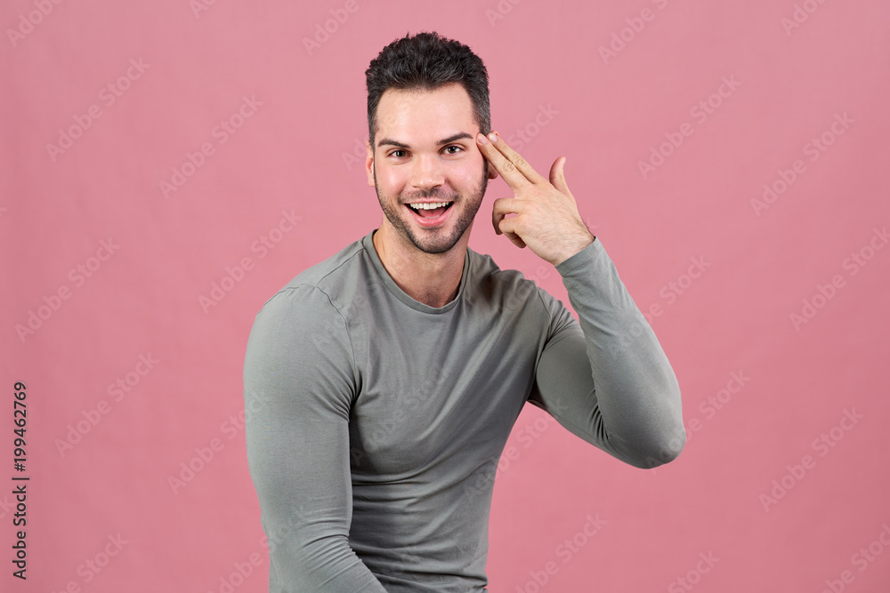 successful young sports man smiles happily and puts his hand folded like a gun to his head. successful young sports man smiles happily and puts his hand folded like a gun to his head.
