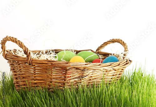 Easter eggs in basket at green grass blades of grass