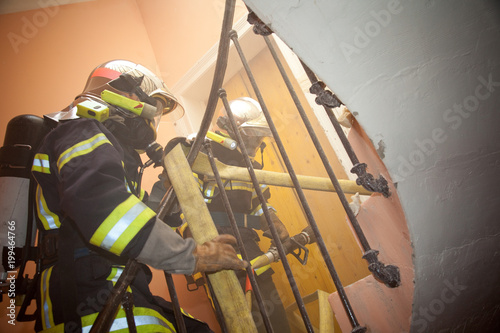 two french firefighter in stair with hose