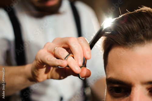 Master cuts hair and beard of men in the barbershop