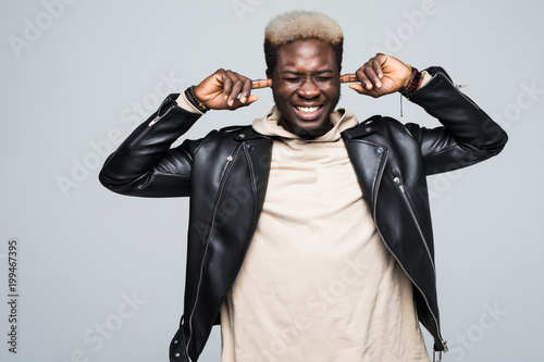 Horizontal shot of young African American male pictured isolated on white background stopping up his ears with sad disappointed face unwilling to hear unpleasant information or face problems photo