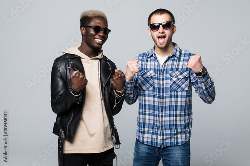 Multuracial friendship. Two men celebrate win isolated on gray background photo