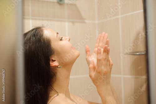 Photo of young beautiful woman taking relaxing shower