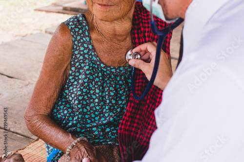 Obraz na plátně Male Doctor listening heart beat and breathing of Elderly Woman with Stethoscope with First Aid Medical Box