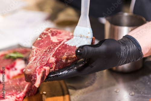 The hands of the chef lubricate raw meat photo