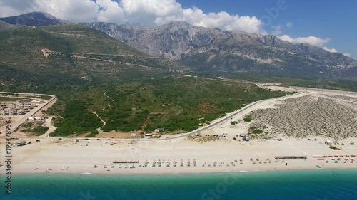 Beach with people relaxing near mountains in Albania photo