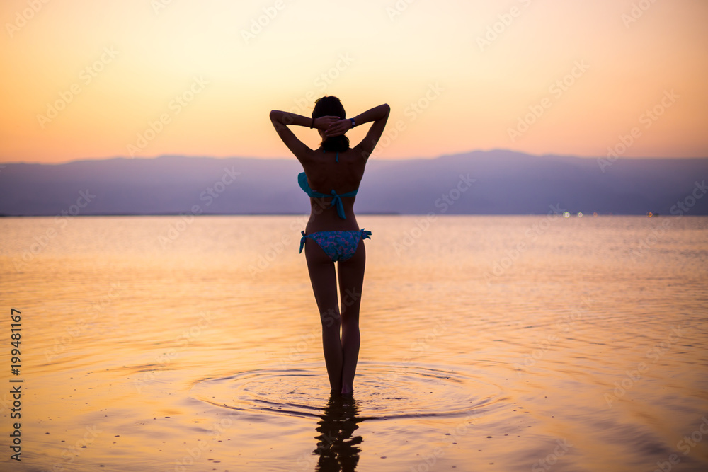 The girl meets the dawn on the dead sea. silhouette of a young girl at the dawn