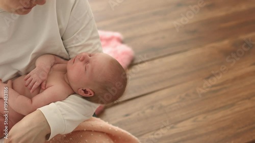 Happy mother looks at her naked sleeping newborn baby with love photo