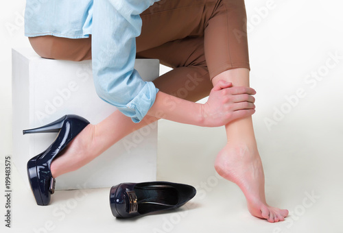 Cropped image of woman in high heels massaging her tired legs