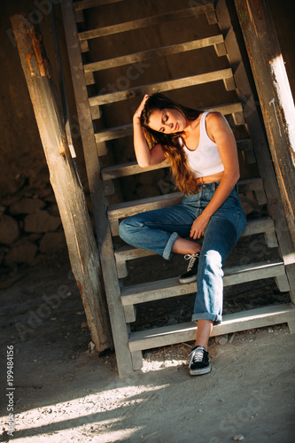 Portrait of an attractive young woman sitting on wood stair in a farm. Lifestyle concept