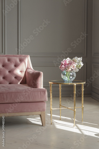 A large beautiful pink sofa stands in a spacious living room in a classic style.