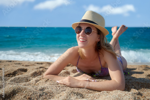 Wallpaper Mural Portrait of a young woman in sunhat and swimsuit is laying on the beach sand against the sea. Torontodigital.ca