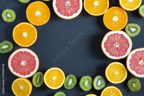 Flat lay. Top view. Sliced colorful  fresh fruits: kiwi, orange, grapefruit and mandarin on black background. Summer background. Copy space.