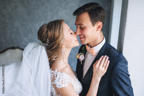 Beautiful newlyweds gently embrace in the studio. Portrait of a newlywed couple.