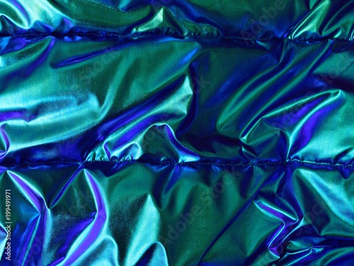 Glossy blue green background with textile texture. Opalescent appearance, modern trend.