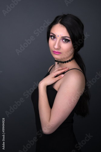 Close up face. Young arabic woman in black sexy dress, isolated on gray background