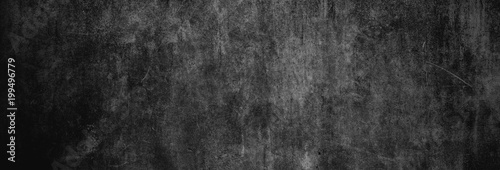 Textur einer fast schwarzen und alten Betonwand als Hintergrund, auf die leichtes Licht fällt photo