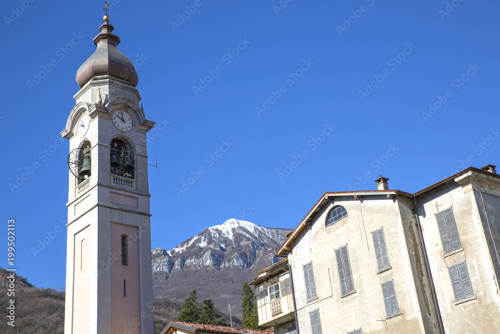 Ancient bell tower with background the Italian Alps