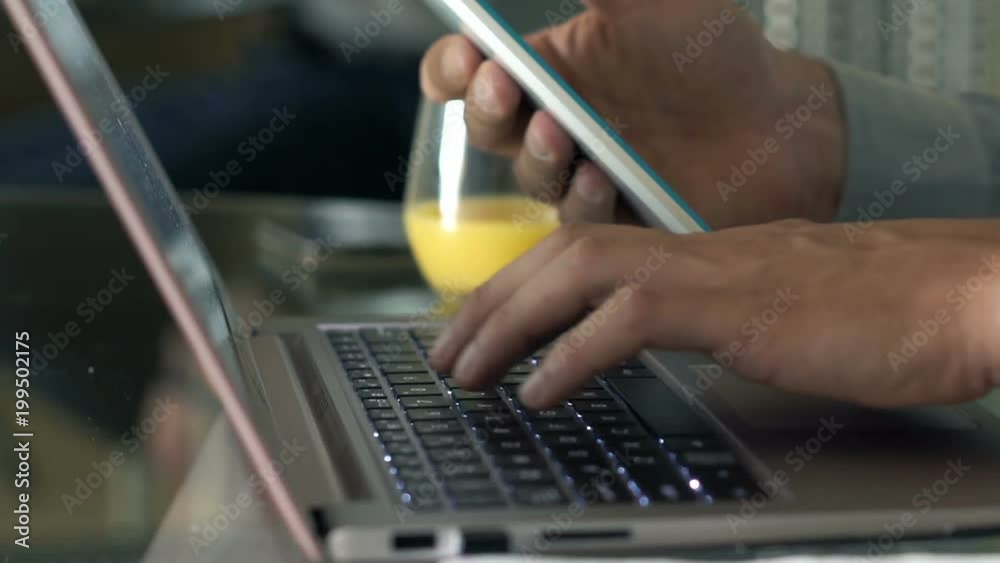 Businessman working with tablet and laptop sitting by table at home
