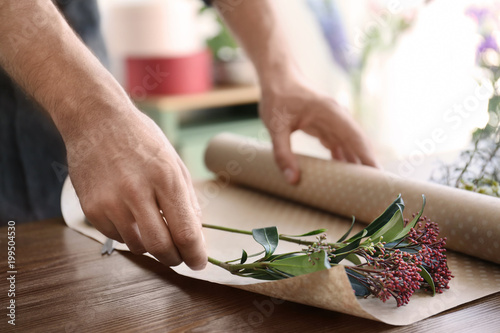 Male florist creating beautiful bouquet at table, closeup