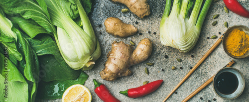 Asian cuisine ingredients over concrete background, top view, wide composition. Flat-lay of vegetables, spices and sauces for cooking vietnamese, thai or chinese food. Clean eating, vegetarian concept