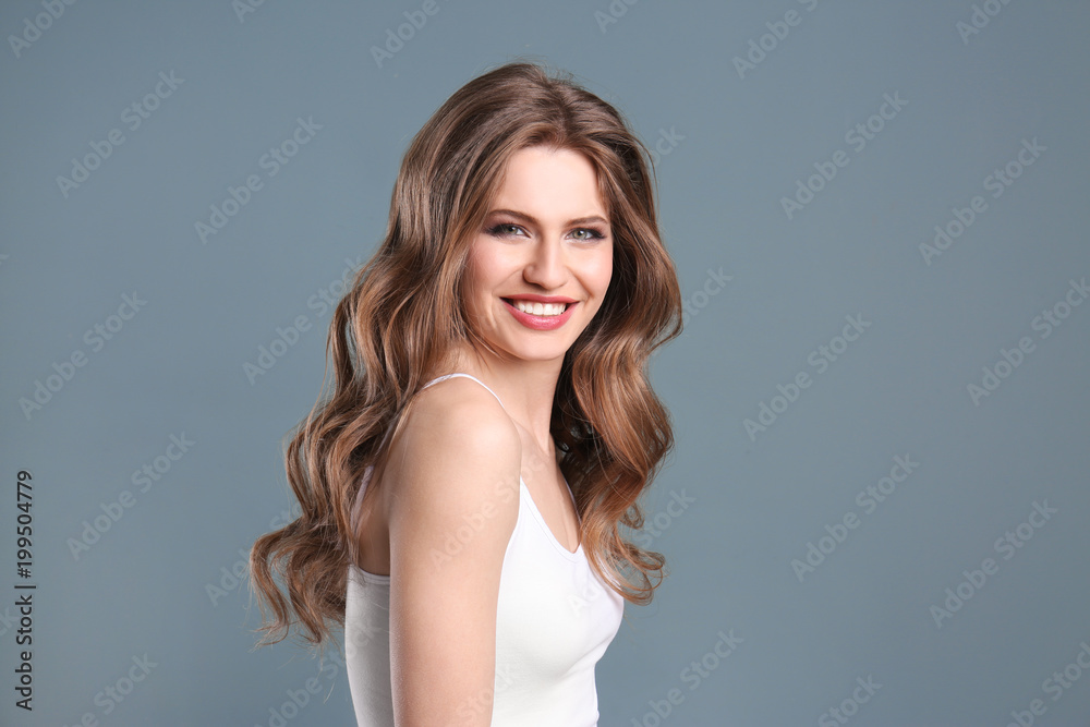 Naklejka premium Portrait of young woman with long beautiful hair on grey background