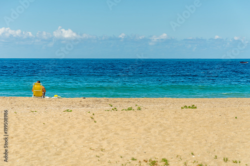 Tourist on the beach sitted on his yellow chair