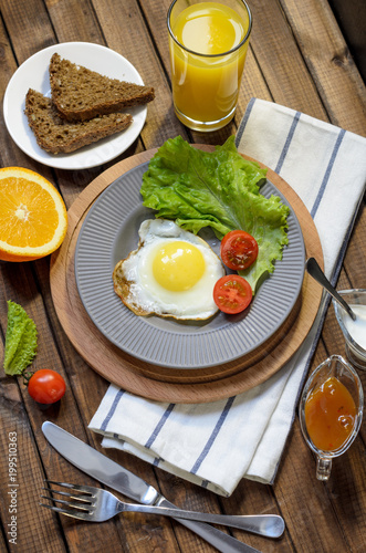 English Breakfast: fried egg, juice, cherry tomatoes, lettuce, grain bread, sauce, top view.