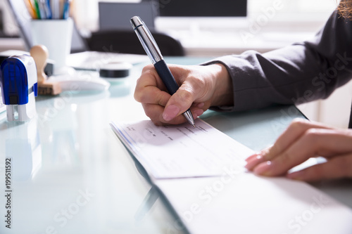 Businessperson Signing Cheque In Office