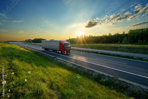 Red truck driving on the highway in the countryside in the rays of the sunset © am