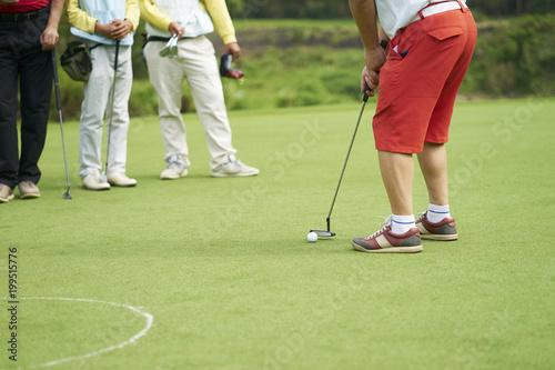 Asian golfer putting on green in summer vacation