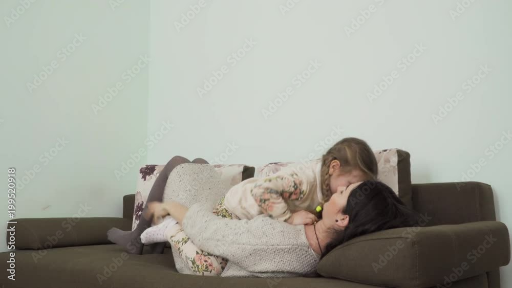 Mother and daughter is fooling around on sofa at home
