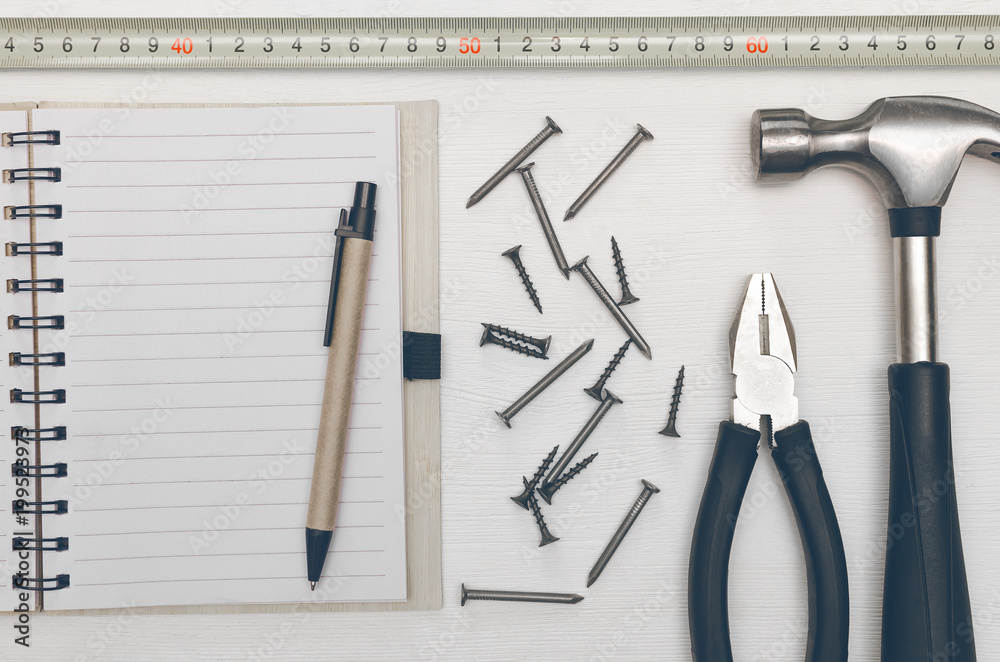 Construction concept background with copy space. Blank note pad with empty paper sheet, pen and hammer with nails on the table. Construction tricks. Construction concept background with copy space. Blank note pad with empty paper sheet, pen and hammer with nails on the table. Construction tricks.