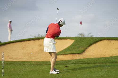 Asian woman playing golf outdoors in course in summer 