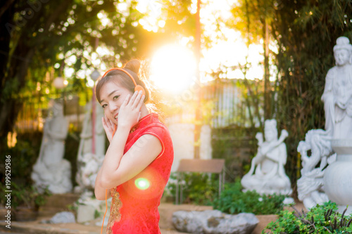 Beautiful Asian girl wearing Cheongsam red dress listening to music be happy. the celebration of something in a joyful and exuberant way. select focus