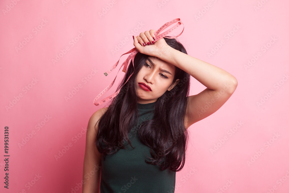 Unhappy young Asian woman with measuring tape.