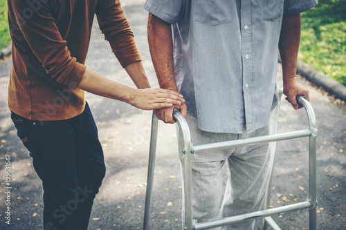 assisting her senior patient who's using a walker for support
