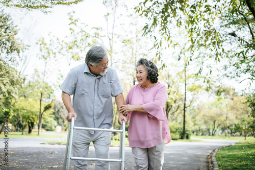 assisting her senior patient who's using a walker for support