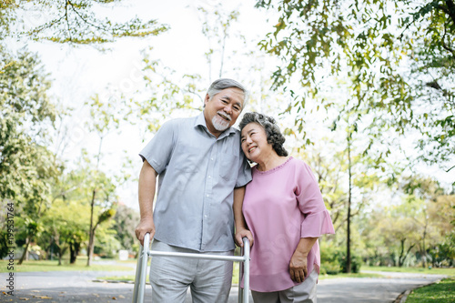 assisting her senior patient who's using a walker for support © Johnstocker