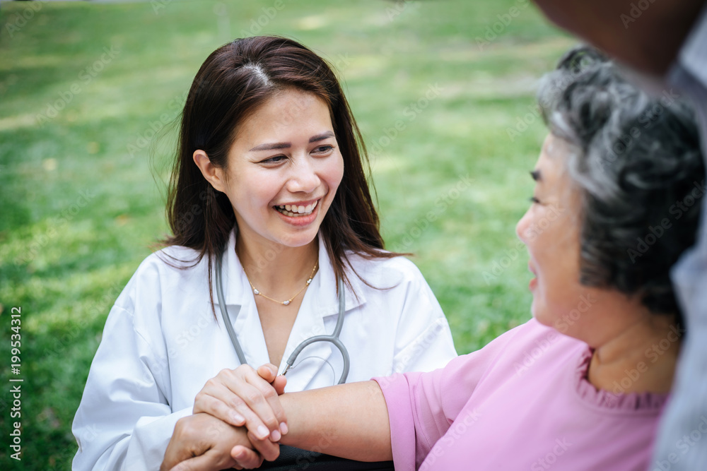 Nurse looking at elderly patient in a wheelchair. Doctor talking to old disabled Nurse looking at elderly patient in a wheelchair. Doctor talking to old disabled