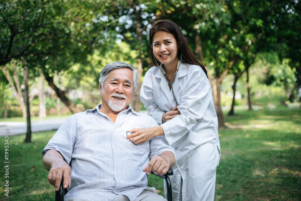Nurse looking at elderly patient in a wheelchair. Doctor talking to old disabled Nurse looking at elderly patient in a wheelchair. Doctor talking to old disabled