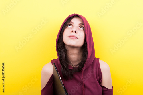 Woman in a hood looking up on yellow background in studio © DC Studio