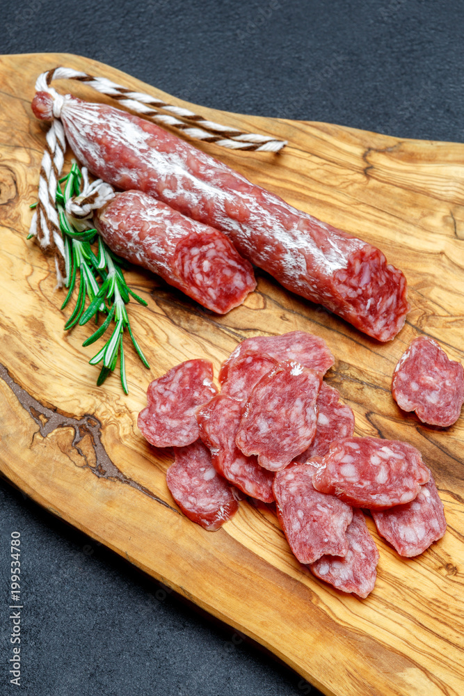 Dried organic salami sausage on wooden cutting board Dried organic salami sausage on wooden cutting board