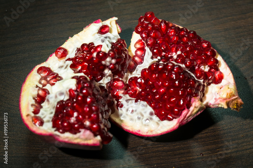 An opened ripe pomegranate fruit with red appetizing juicy seeds, seperating from the peel. photo