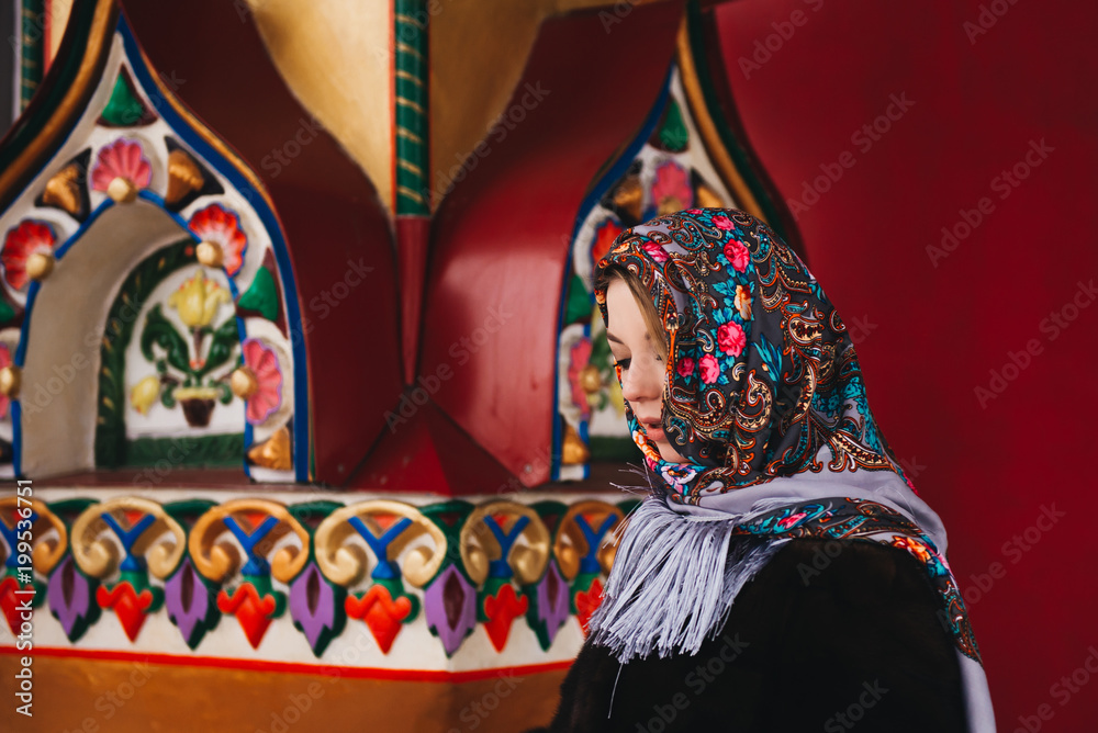 A young beautiful girl in a mink coat and a Russian folk scarf walks around the Izmailovo Kremlin. Moscow, Russia.
