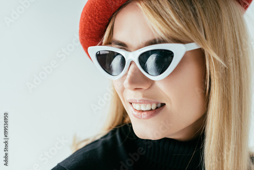 Attractive young woman in red beret and sunglasses isolated on grey