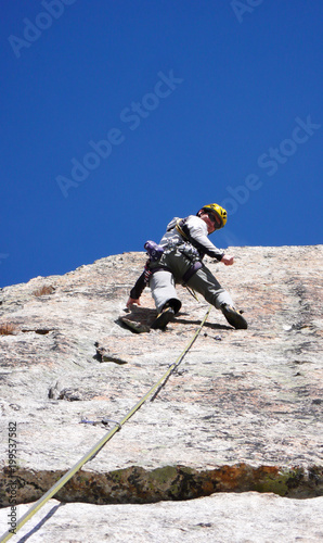 mountain guide rock climber on a steep granite route in the Alps of Switzerland on a beautiful day