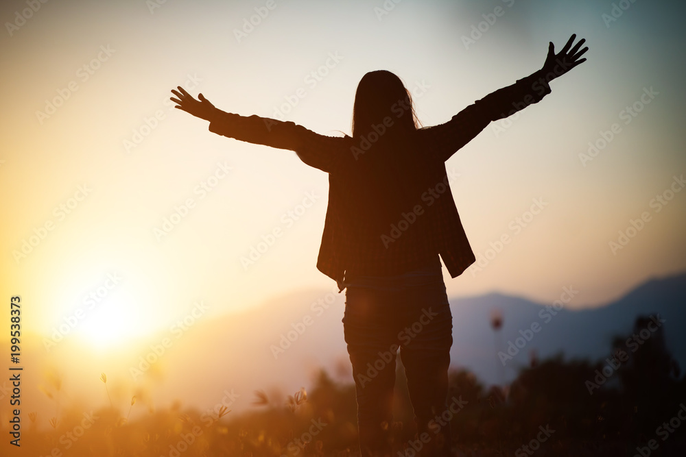 Silhouette of woman praying over beautiful sky background