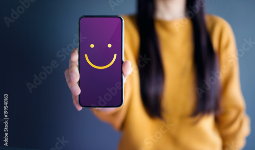 Customer Experience Concept, Happy Woman Show Smiley Face for her Satisfaction on Smart Phone photo