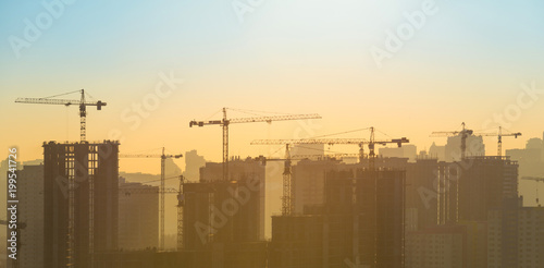 Panoramic view of sunset in the city with silhouette of buildings and industrial cranes